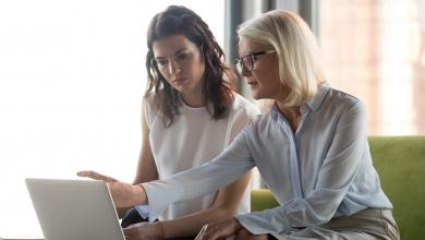 认真的中年执行经理，解释同事在线工作，指向笔记本电脑