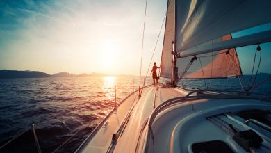 年轻人站在日落的海洋游艇上